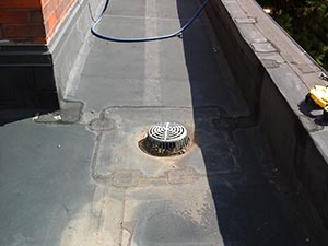 Roof-Maintenance-McKinney-TX-Texas-2 | Anderson Industrial Roofing Flat rooftop with a circular roof drain grate in the center; a blue hose and a yellow tool rest along the edge.