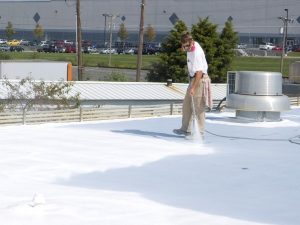 man spraying white coating on flat roof - roof coating Irving TX | Roof Coating Irving, TX | Anderson Industrial Roofing